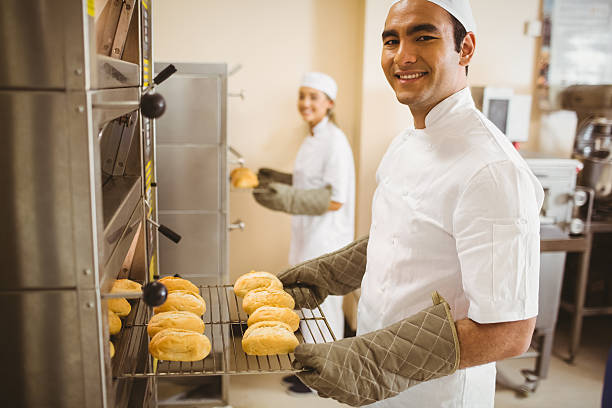 istock Baker smiling at camera taking rolls out of oven 532574019