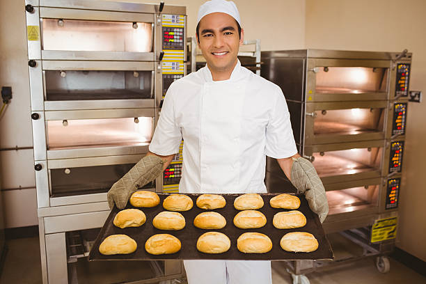 istock Baker smiling at camera holding tray of rolls 532574105