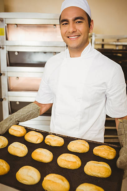 istock Baker smiling at camera holding tray of rolls 532574143