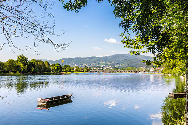 Boat seen along the Lima river near ponte de lima bridge, seen in the distance, Riverside nature landscape. Situated in the Minho region north of Portugal, a popular tourist destination.