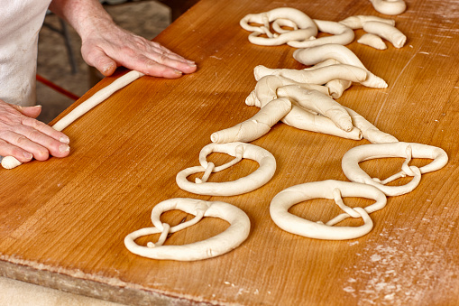 View of bakery table on hand of a person making pretzels