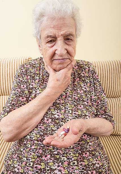 плохо пожилая женщина принимая таблетки - vitamin pill picking up pill capsule стоковые фото и изображения