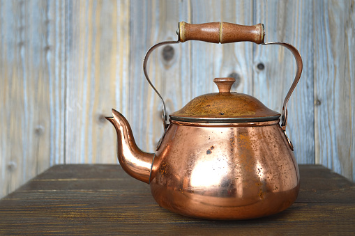 Old copper teapot on wooden table