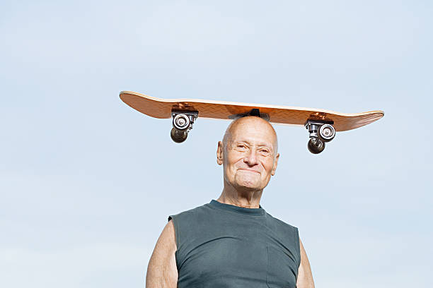 Man with skateboard on his head Man with skateboard on his head young at heart stock pictures, royalty-free photos & images