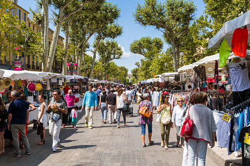 Aix en Provence, France - August 19, 2014: Many people (tourists and others) walking on Cours Mirabeau in Aix en Provence during the summer season. Many market stands on the left and on the right.