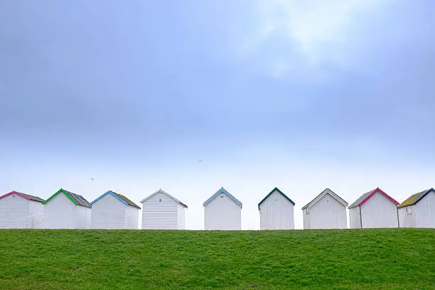Picture of some white beach huts with grass in the foreground