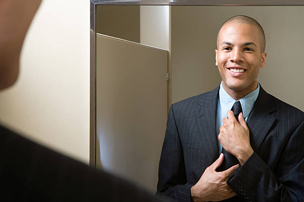 Man adjusting tie in mirror Man adjusting tie in mirror day 1 stock pictures, royalty-free photos & images