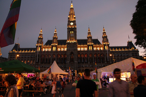 Vienna, Austria - June 12, 2014: The 2014 Gay Pride celebration in front of the Vienna City Hall, also known as the Rathaus, at night. Partiers, locals and tourists circulate among tents and booths.