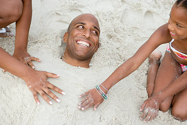 família enterrar pai na areia - burying ground imagens e fotografias de stock