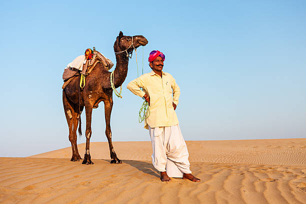 istock Indian man with camels during crossing sandunes 532665361