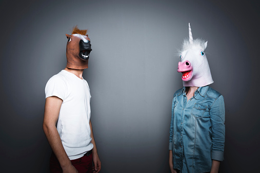 Front view of aged 20-29 years old caucasian young male manager standing in front of white background wearing costume with hand by side and wearing horse mask