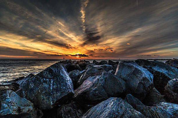 Sunset on the rocks Sun setting over the rocks on a winters evening. clacton on sea stock pictures, royalty-free photos & images