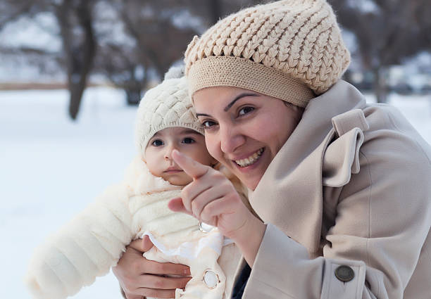 Young mother playing with her daughter in a winter day.