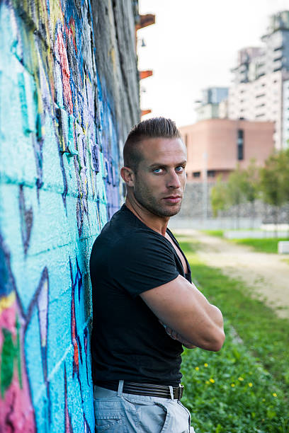 istock Handsome muscular man leaning against colorful graffiti wall 532704189