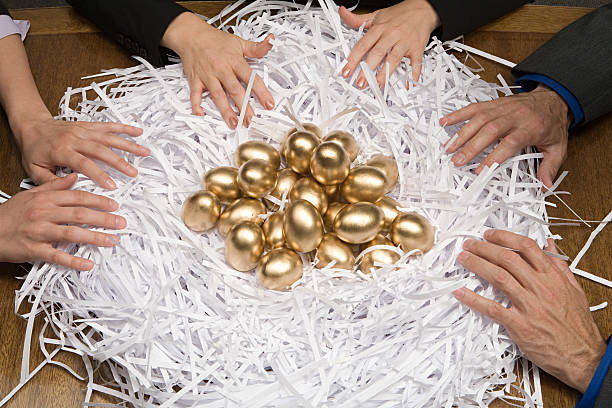 kollegen um ein nest mit goldene eier - animal egg gold human hand nest egg stock-fotos und bilder