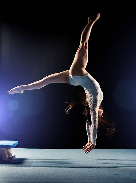 Young woman doing gymnastics jump Young woman doing gymnastics jump gymnastics stock pictures, royalty-free photos & images