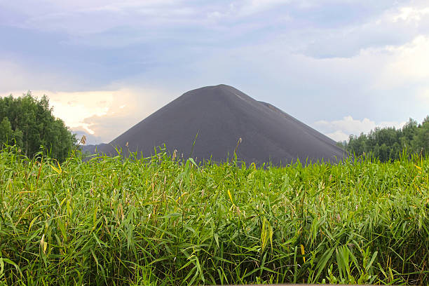 Slag heap Slag heap with green field slag heap stock pictures, royalty-free photos & images