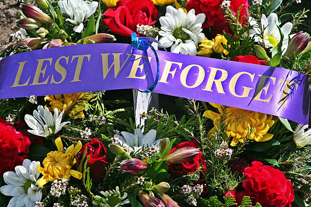 ANZAC Rememberance Day - Lest We Forget Floral Wreath A brightly coloured floral wreath and 'Lest We Forget' memorial sash placed on an ANZAC Day Cenotaph memorial.  larrikin stock pictures, royalty-free photos & images