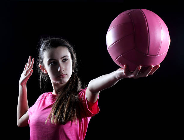 Young volleyball player on black background A young female volleyball player is poised to serve. young volleyball girl stock pictures, royalty-free photos & images