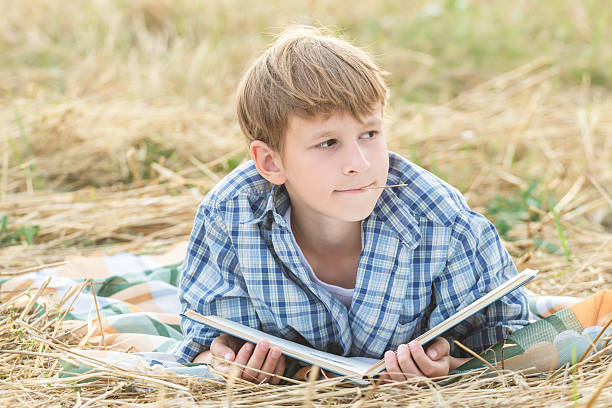 Teenage boy soñando libro de lectura - foto de stock
