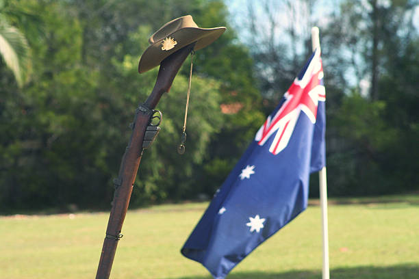 ANZAC Day Army Rifle, Slouch hat, Dogtags and Australian Flag Landscape shot (with room for copy) of an upturned, vintage Australian Army 303 rifle, a soldier's dogtags, slouch hat with an Australian Flag flying in the background during an ANZAC Day memorial service. larrikin stock pictures, royalty-free photos & images