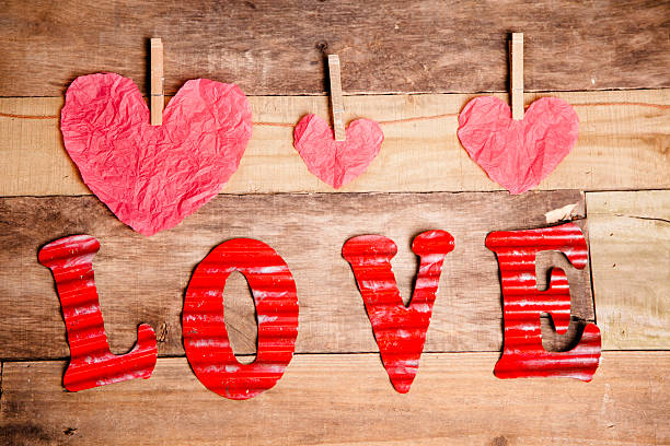 istock Valentine's Day paper hearts, string. Letters spell LOVE. Wooden table. 532751693