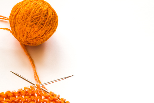 Knitting, orange wool on white background
