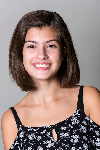 Smiling teenage girl looking at the camera on gray background