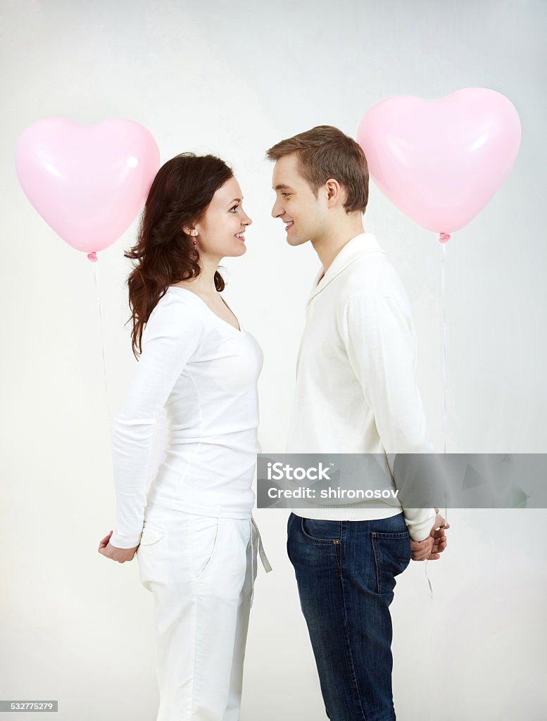 Amorousness Two beautiful young people with heart-shaped balloons looking at each other Adult Stock Photo