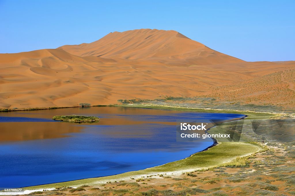 Lake in Badain Jaran desert, Inner Mongolia Badain Jaran desert huge sand dunes and lake. This desert is home to some of the tallest stationary dunes on Earth, some reaching a height of more than 500 meters. The desert features over 100 lakes that lie between the dunes, some of which are fresh water while others are extremely saline.  2015 Stock Photo