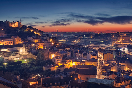 View over the city of Lisbon in Portugal, as night falls. The São Jorge Castle can be seen on the hill on the left.