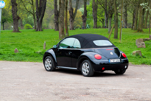 Essen, Germany - April 10, 2014: A black VW Beetle convertible car is parked in front of small park at riverside of Ruhr in Essen Werden. Spring morning shot.