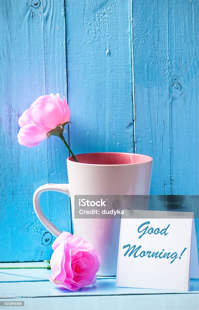 Mug with roses on blue wood background with good morning text Mug with pink roses on blue wood background with good morning text 2015 Stock Photo