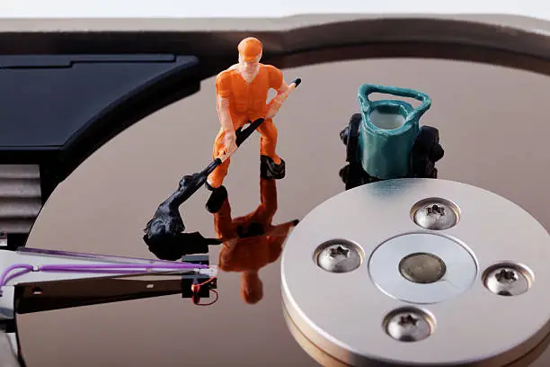 Small scale generic train model worker on a surface of a computer hard drive. Concept of repairing or cleaning computer hard drive.