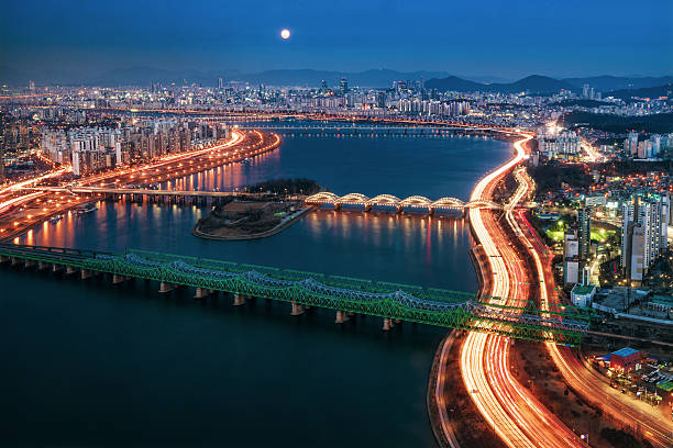 Seoul cityscape at dusk The Repbulic of Korea's capital city, Seoul seen from a high angle view along the Han River, with a full moon over the mountains on the horizon. kangnamgu stock pictures, royalty-free photos & images