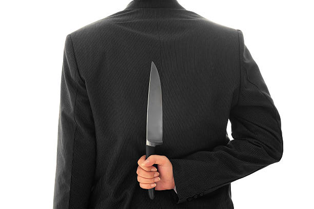 istock Businessman Holding Knife Behind His Back conceptual image Isolated 532834087