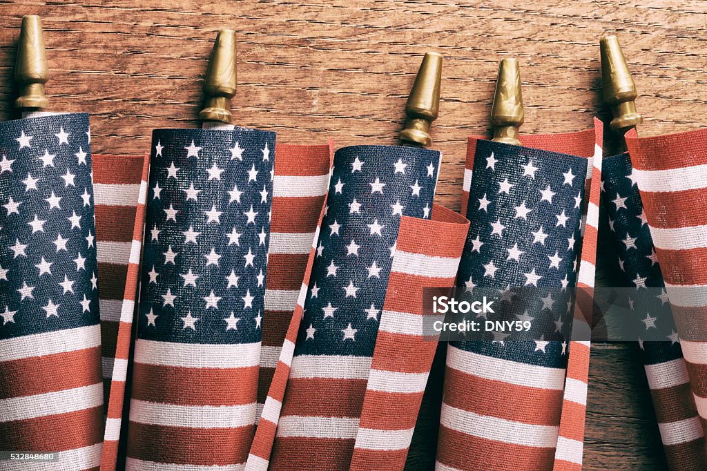 Row Of Small Curled American Flags A row of five, small, curled up American flags on a richly tectured wood surface. American Flag Stock Photo