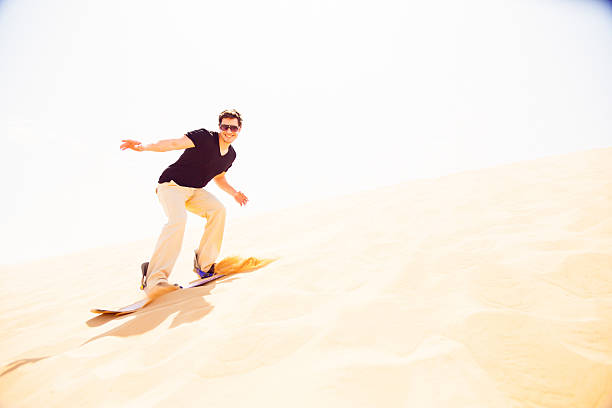 tourist sandboarding in the desert