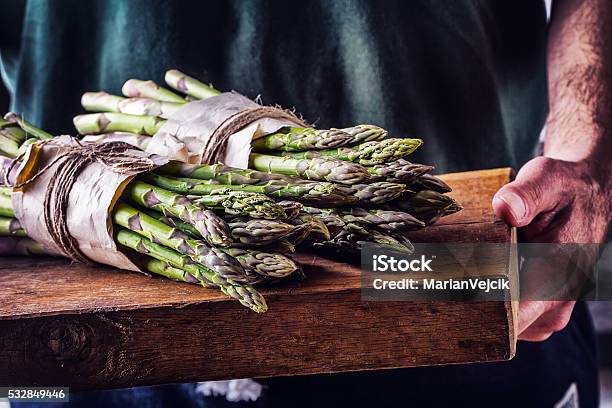 Farmer Carries Tied Asparagus On A Wooden Board Stock Photo - Download Image Now - Chef, Food, Springtime