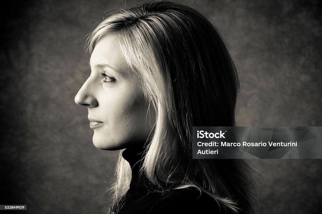 Profile of woman in studio, gray background and dramatic light Young woman, profile. Gray muslin background. Studio shot. Toned. 20-24 Years Stock Photo