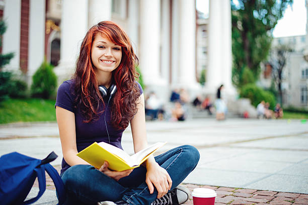 student girl libro de lectura frente de univercity - back to school young women cheerful happiness fotografías e imágenes de stock