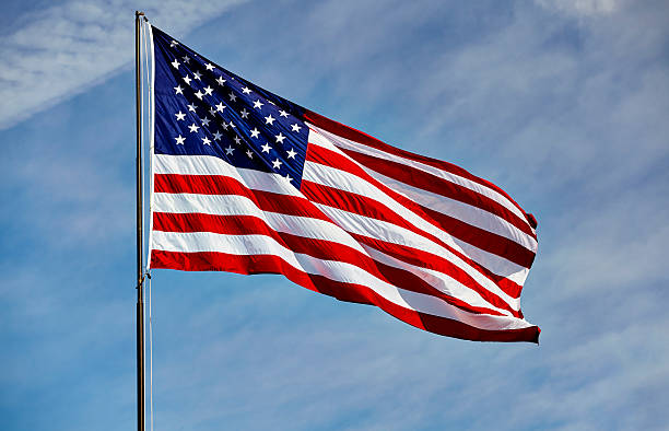 istock Flag USA in wind on flagpole with sky 532850334