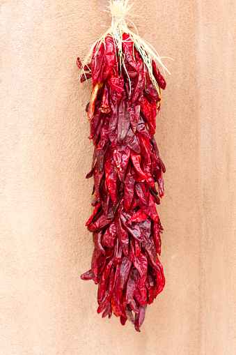 Santa Fe style: Chile pepper ristra hangs on a brown adobe wall. Copy space available.
