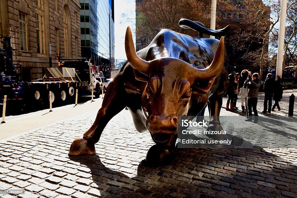 Charging Bull New York, NY, USA - November 19, 2014: Charging Bull: The Charging Bull of Wall Street bronze statue located on Broadway Street in the Financial District of Lower Manhattan in New York City, New York, USA. Skyscrapers in background. Daytime image. Wall Street - Lower Manhattan Stock Photo