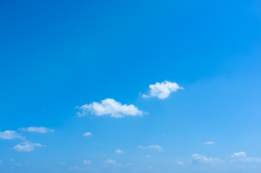 Small white clouds in clear blue sky background