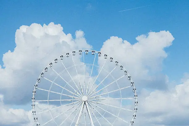 Ferris wheel against beautiful white clouds and blue sky background on summer time