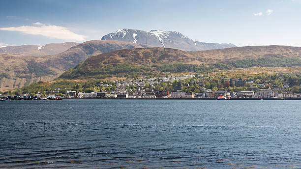 Fort William and Ben Nevis Ben Nevis, the UK's highest mountain, rises behind Loch Linnhe, with the town of Fort William on the sea shore. fort william stock pictures, royalty-free photos & images