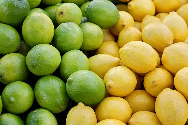 A basket of fresh, ripe yellow lemons and green limes are gathered together on a fruit sale table at a Farmer's Market in Marco Island, Florida.