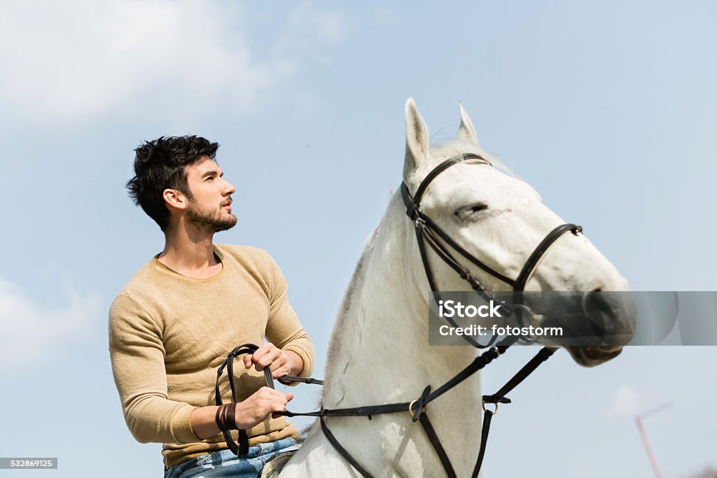 Young man riding a horse Young man riding white horse. Cowboy Stock Photo