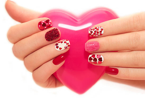 Manicure with hearts Manicure with rhinestones in the shape of hearts and pink balls on white and red nail Polish on a white background. heart designs nails stock pictures, royalty-free photos & images